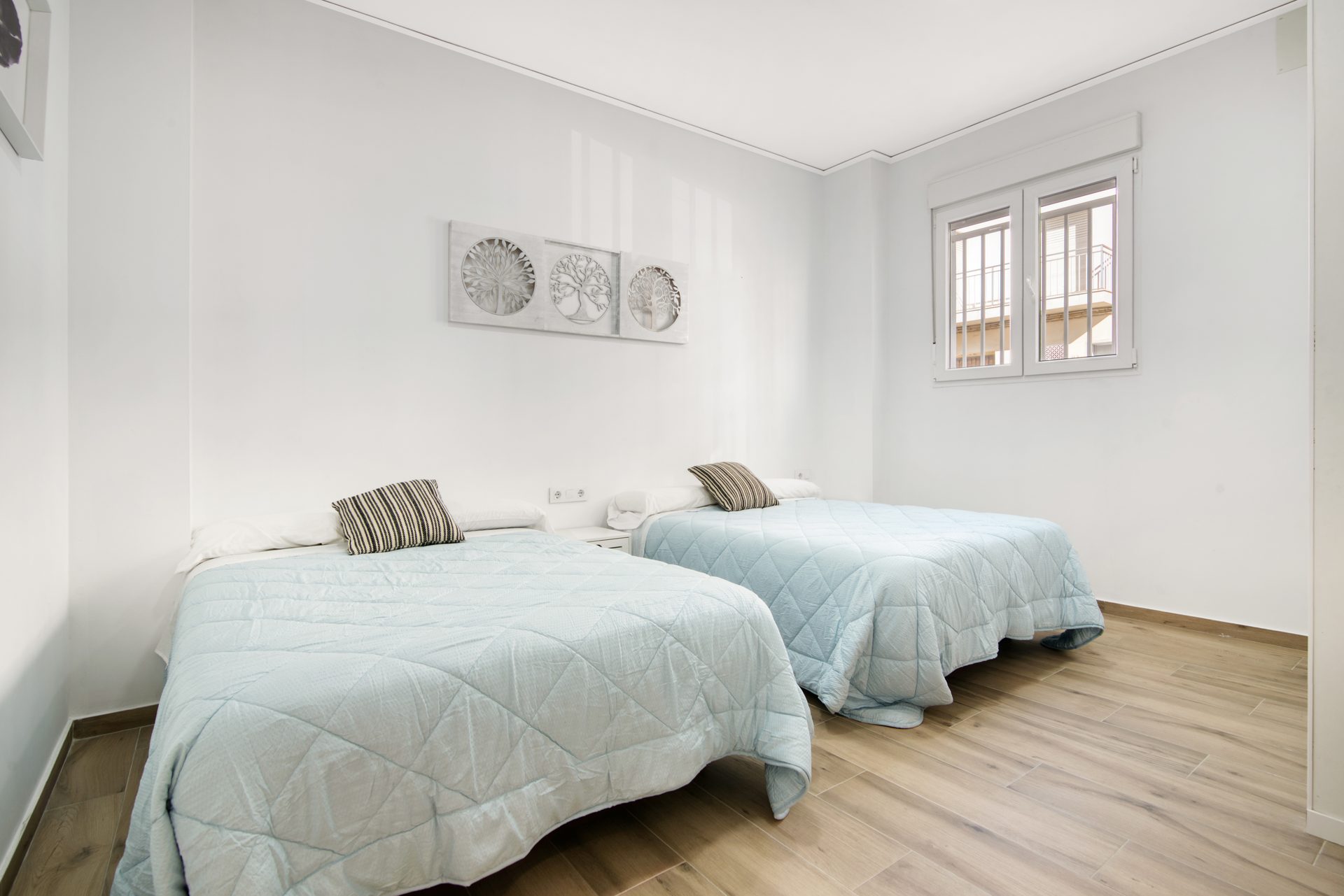 Habitación con dos camas y suelo de madera clara