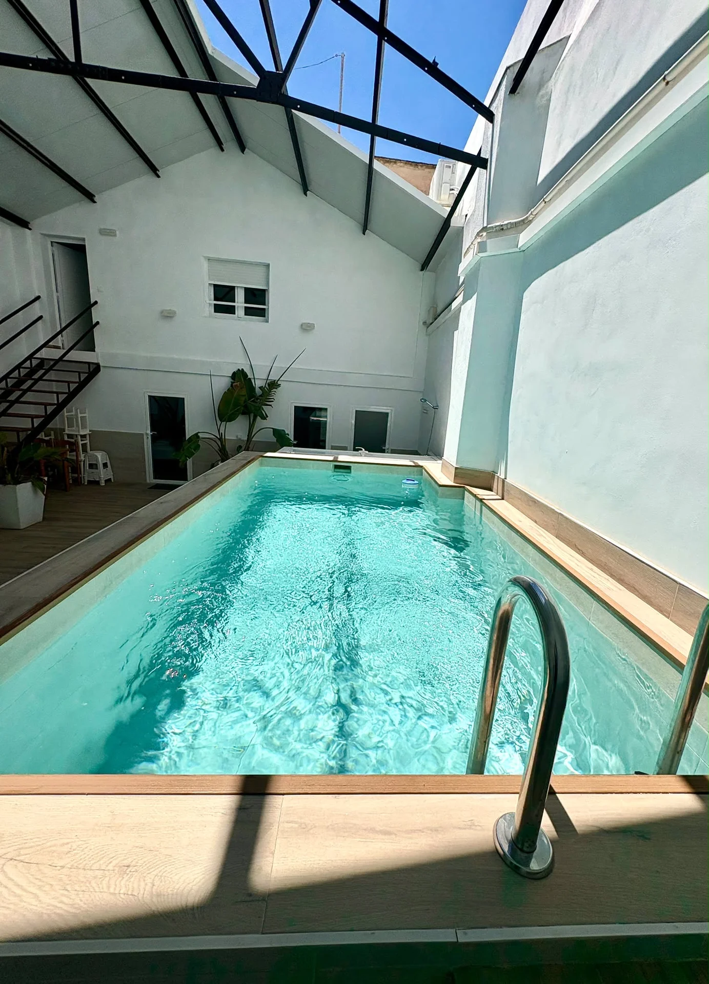 Vista general de la piscina climatizada en patio interior con lucernario metálico y escaleras al fondo — Vivienda Lope de Vega Gandía