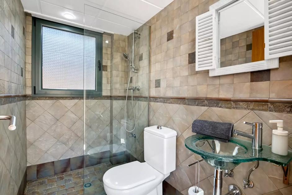 Baño con ducha de cristal y lavabo de diseño