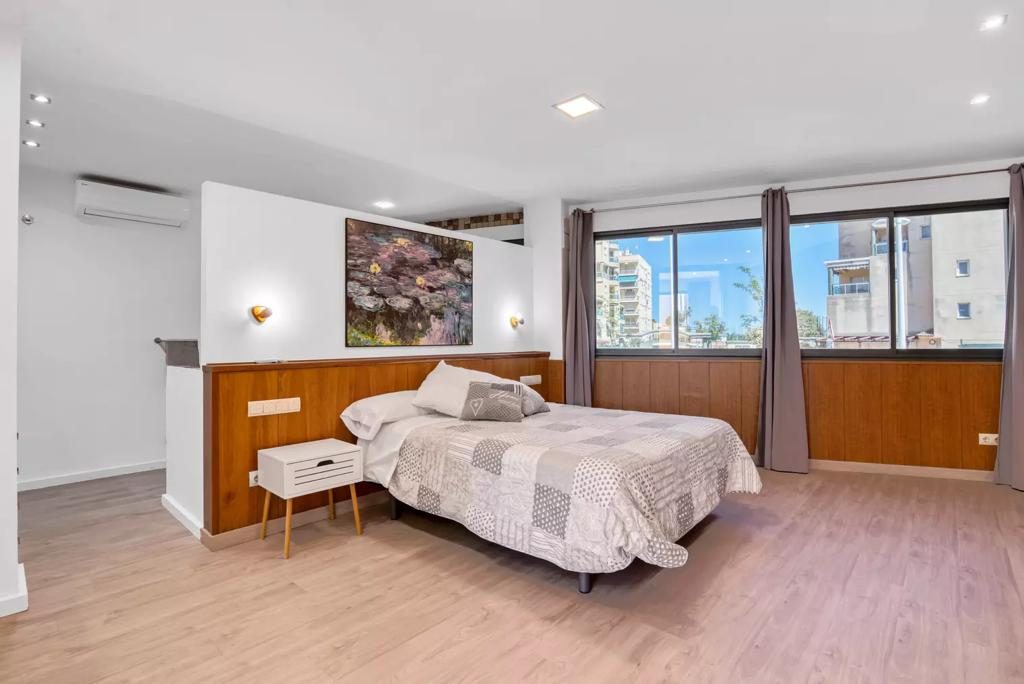 Habitación principal con cama de matrimonio y ventanas amplias