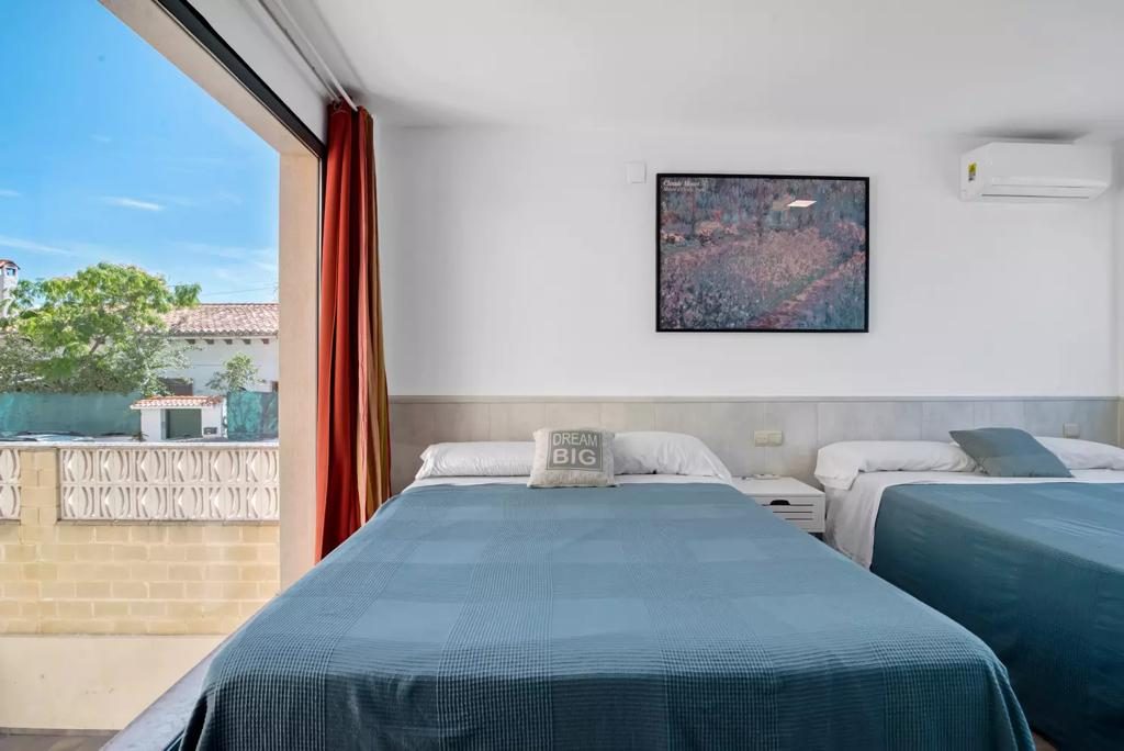 Habitación con dos camas y vistas al exterior soleado